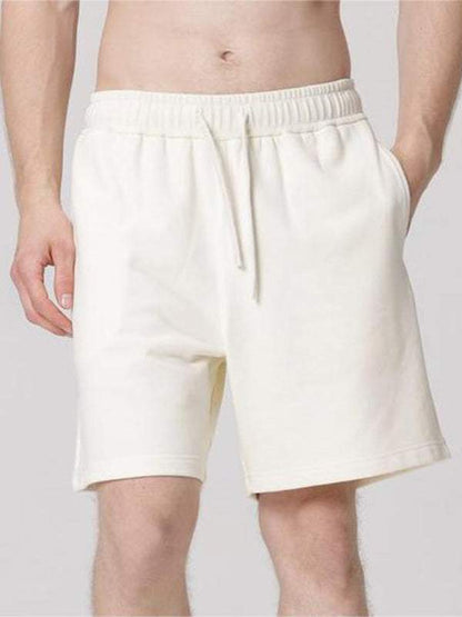 Men's solid color loose casual sports shorts with elastic waistband and slant pockets, ideal for spring-summer activities.