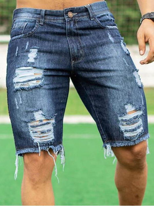 Men's slim fit denim shorts with distressed detailing on a grassy field.