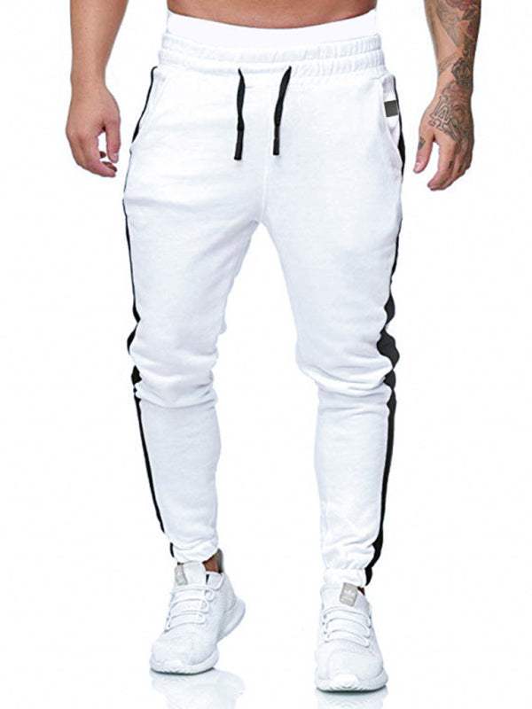 Men's sports color block casual trousers with slant pockets, white with black side stripes.